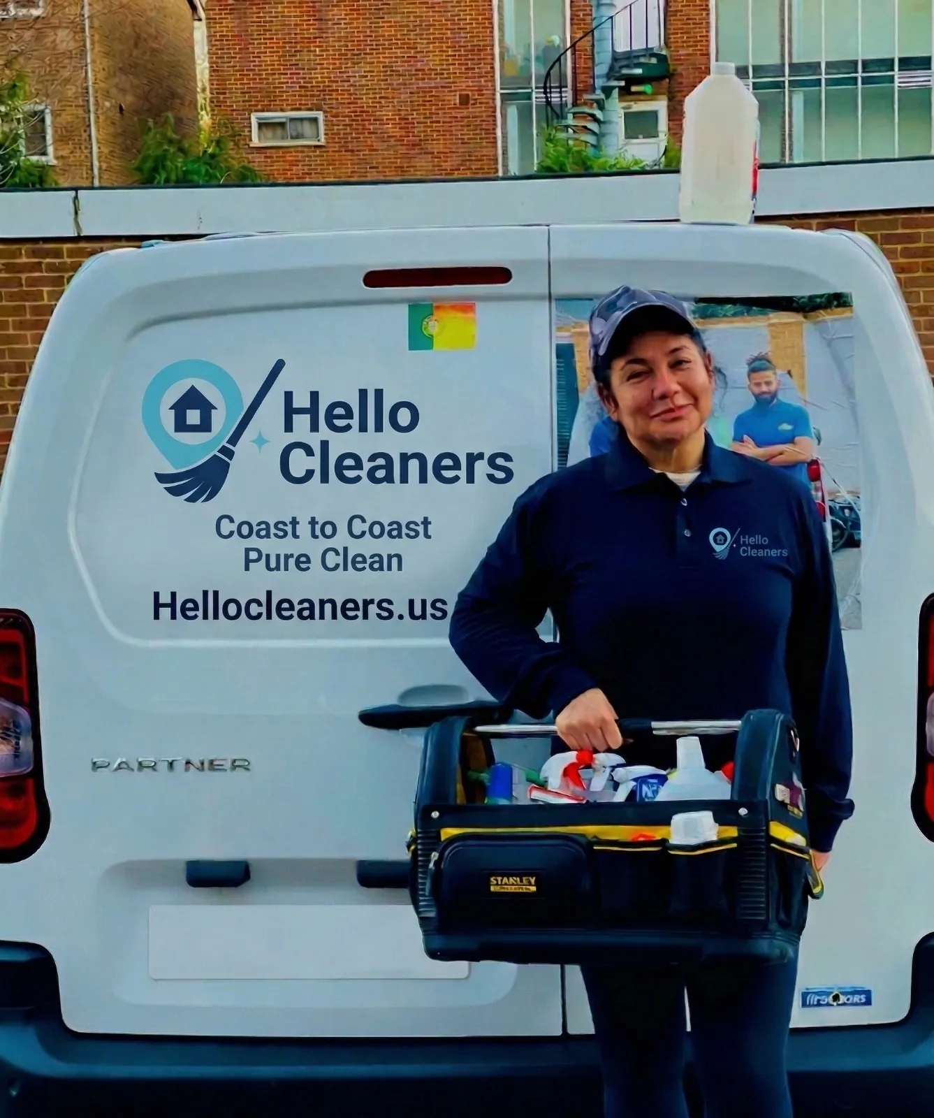 Hello Cleaners cleaner carrying a full cleaning supply kit at the back of a branded van